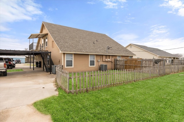 exterior space featuring central air condition unit, a shingled roof, a lawn, stairway, and fence