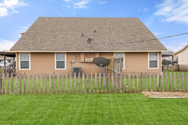 rear view of house with roof with shingles, a lawn, fence, and central AC unit