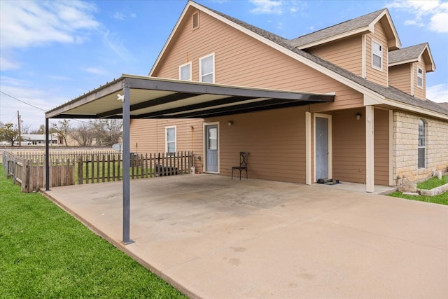 view of home's exterior with a yard, an attached carport, and fence