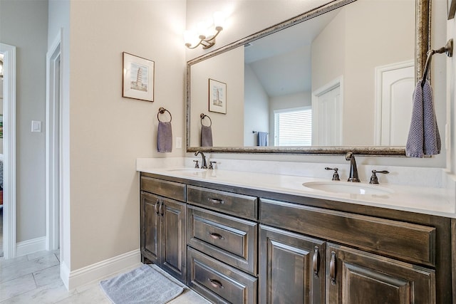 bathroom featuring vaulted ceiling, double vanity, a sink, and baseboards