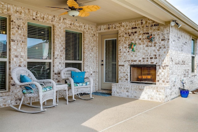 view of patio featuring an outdoor brick fireplace and ceiling fan