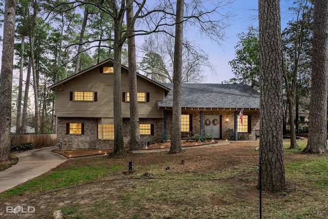 tri-level home featuring fence and brick siding