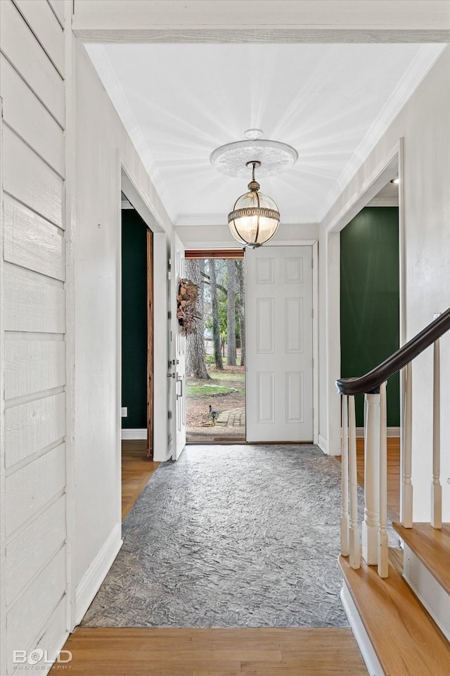 foyer entrance with baseboards, stairs, ornamental molding, and wood finished floors