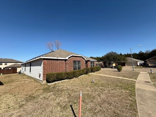 view of side of home featuring brick siding and fence