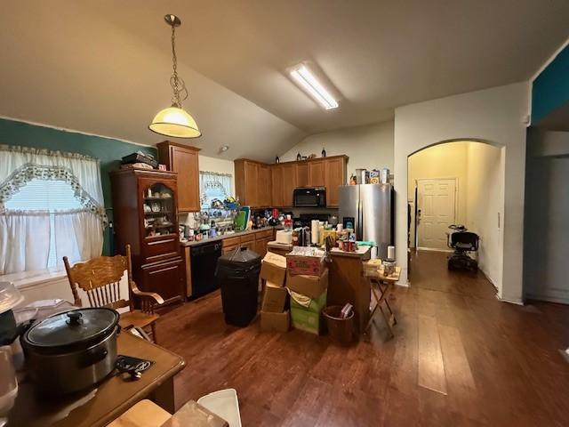 kitchen with arched walkways, dark wood-style flooring, lofted ceiling, hanging light fixtures, and black appliances