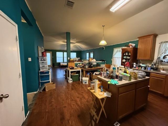 kitchen with dark wood-style flooring, visible vents, light countertops, a center island, and pendant lighting