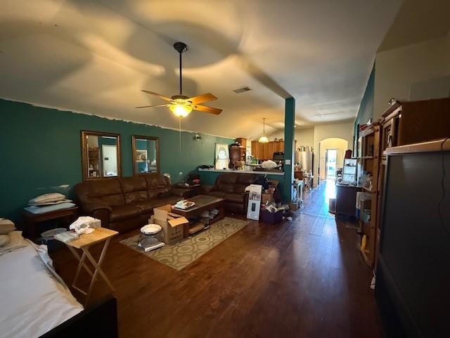 living room featuring arched walkways, ceiling fan, lofted ceiling, dark wood-type flooring, and visible vents