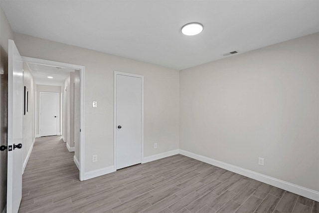 empty room featuring wood finished floors, visible vents, and baseboards