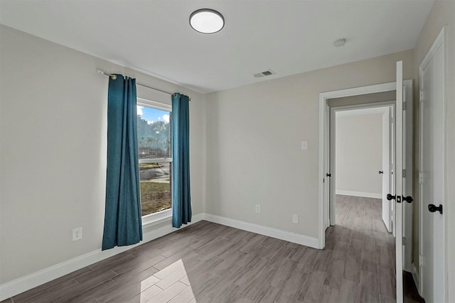 unfurnished room featuring wood finished floors, visible vents, and baseboards