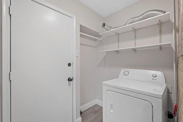 clothes washing area with washer / dryer, laundry area, light wood-style floors, and baseboards