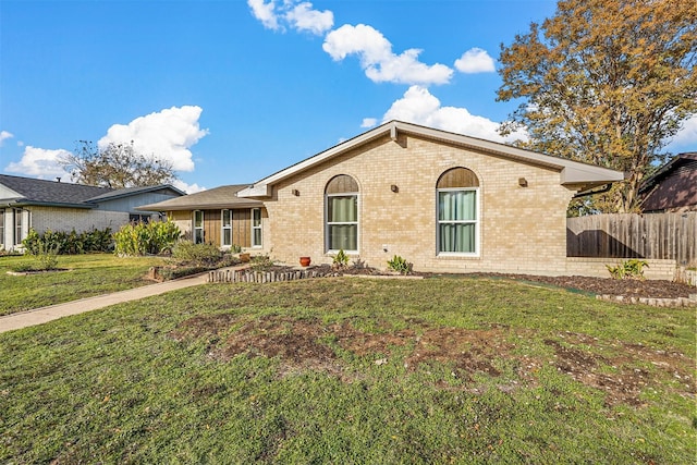 view of front of property featuring brick siding, fence, and a front lawn