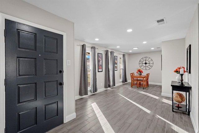 foyer featuring wood tiled floor, visible vents, baseboards, and recessed lighting