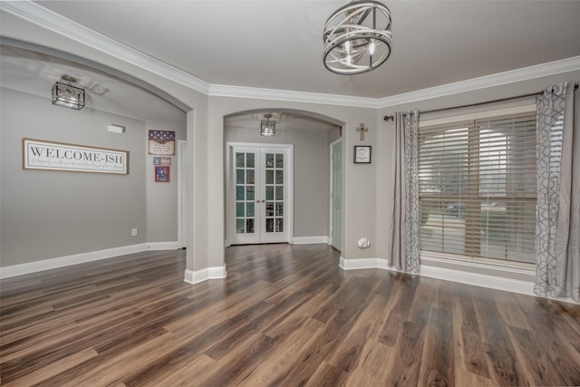 unfurnished dining area featuring wood finished floors, french doors, arched walkways, crown molding, and baseboards