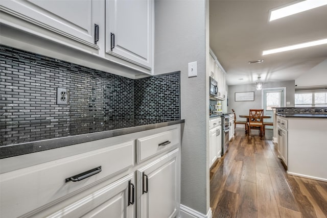 kitchen featuring dark countertops, dark wood finished floors, double oven range, and white cabinets