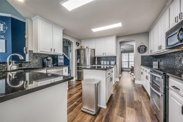 kitchen featuring a sink, dark wood-style floors, arched walkways, and stainless steel appliances