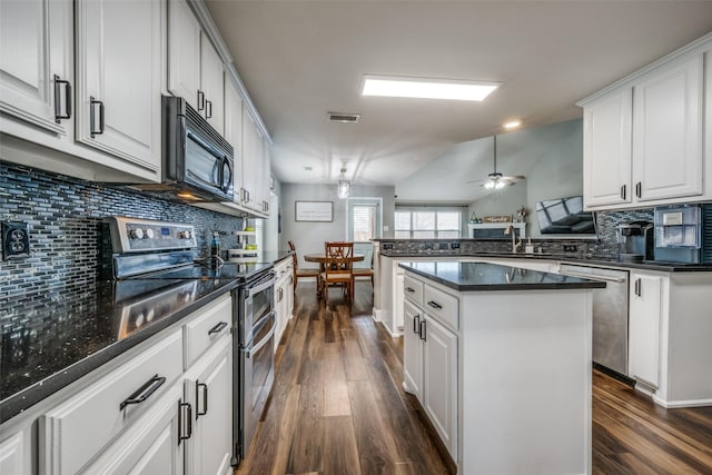 kitchen featuring visible vents, dark wood-type flooring, decorative backsplash, appliances with stainless steel finishes, and a peninsula