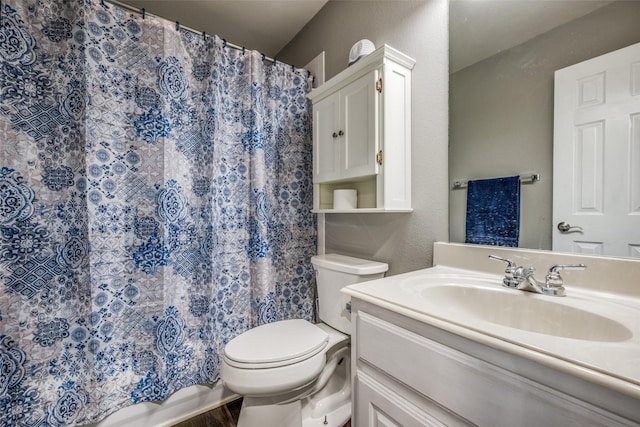 bathroom with vanity, toilet, and a textured wall