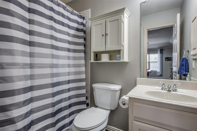 bathroom featuring vanity, a shower with shower curtain, toilet, and a textured wall