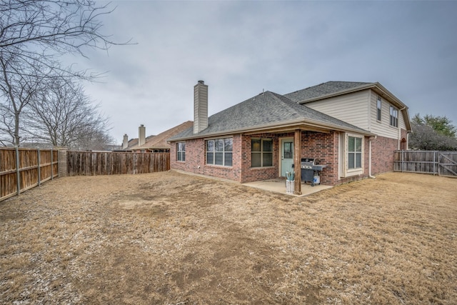 back of house featuring a fenced backyard, a shingled roof, a chimney, a patio area, and brick siding