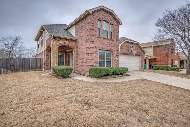 traditional-style home with fence, roof with shingles, concrete driveway, an attached garage, and brick siding