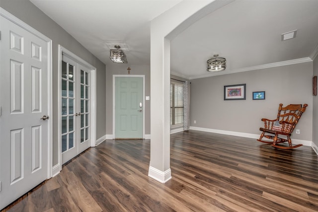 entryway with visible vents, baseboards, dark wood finished floors, ornamental molding, and arched walkways