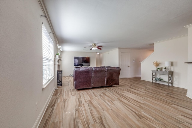 living area with a ceiling fan, baseboards, and light wood finished floors