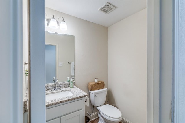 half bathroom featuring visible vents, vanity, and toilet
