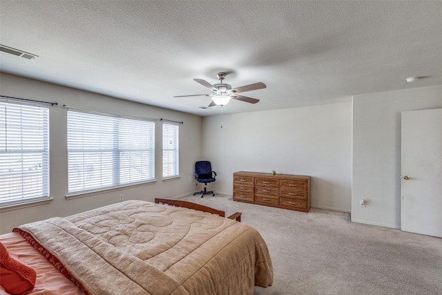carpeted bedroom featuring a ceiling fan, baseboards, visible vents, and a textured ceiling