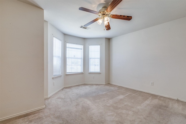 empty room with a ceiling fan, visible vents, and light colored carpet