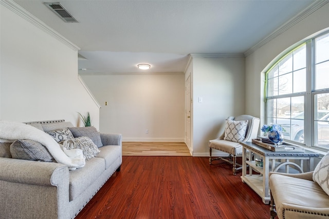 living room with baseboards, wood finished floors, visible vents, and crown molding