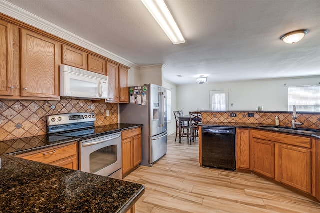 kitchen with a sink, appliances with stainless steel finishes, light wood-type flooring, backsplash, and brown cabinets
