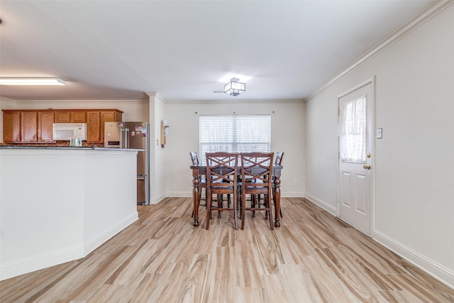 dining area with light wood-style flooring, baseboards, and crown molding