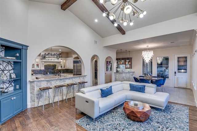 living room with arched walkways, high vaulted ceiling, a notable chandelier, wood finished floors, and beam ceiling