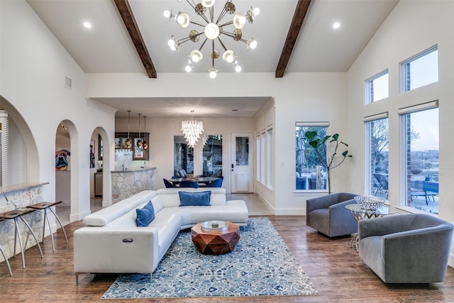 living room featuring wood finished floors, visible vents, beamed ceiling, and an inviting chandelier