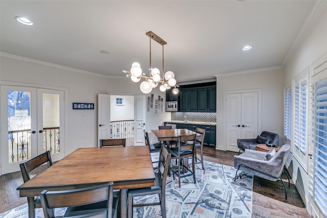 dining area with a notable chandelier, french doors, wood finished floors, and crown molding