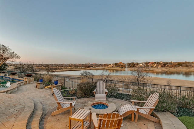 view of patio / terrace with a water view, fence, and a fire pit