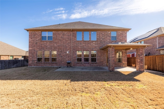 back of property featuring a yard, a patio, brick siding, and a fenced backyard