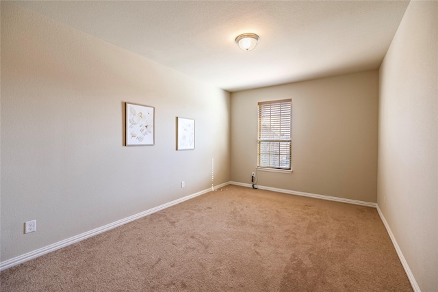 spare room featuring baseboards and light colored carpet