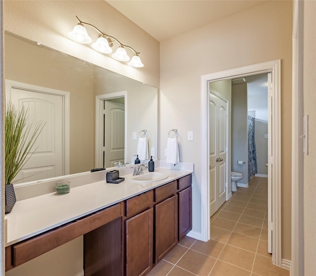 bathroom featuring toilet, vanity, baseboards, and tile patterned floors