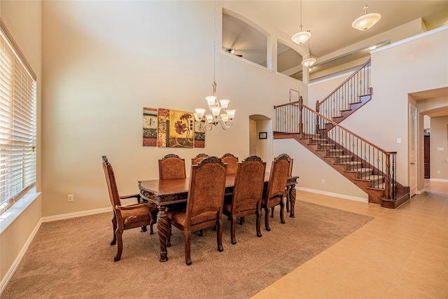 dining room featuring stairs, a high ceiling, a chandelier, and baseboards