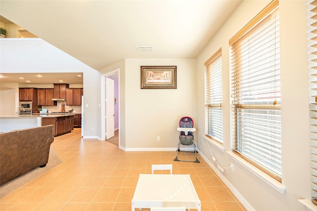 living area with light tile patterned floors, a wealth of natural light, visible vents, and baseboards