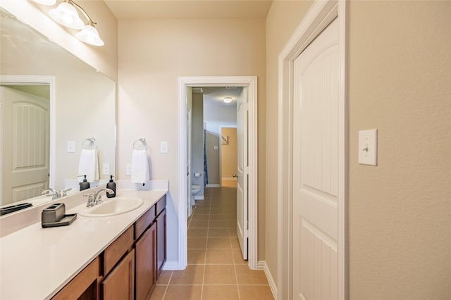 bathroom featuring toilet, tile patterned flooring, baseboards, and vanity