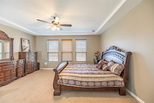 carpeted bedroom featuring a raised ceiling, visible vents, ceiling fan, and baseboards