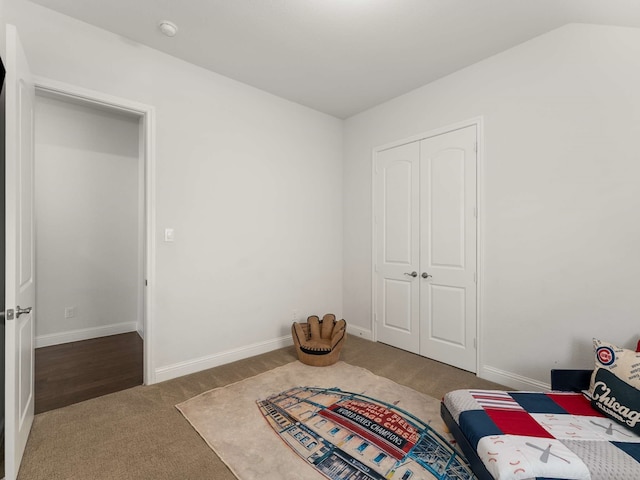 bedroom featuring lofted ceiling, a closet, carpet flooring, and baseboards