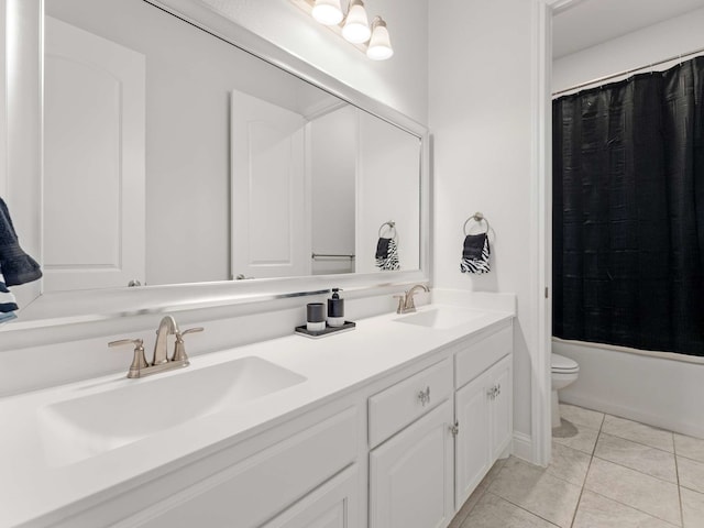 bathroom with tile patterned floors, a sink, toilet, and double vanity