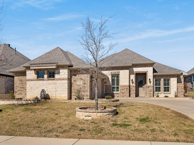 french provincial home with a shingled roof, brick siding, and a front lawn