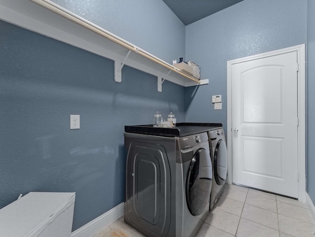 laundry room featuring laundry area, baseboards, separate washer and dryer, and light tile patterned flooring