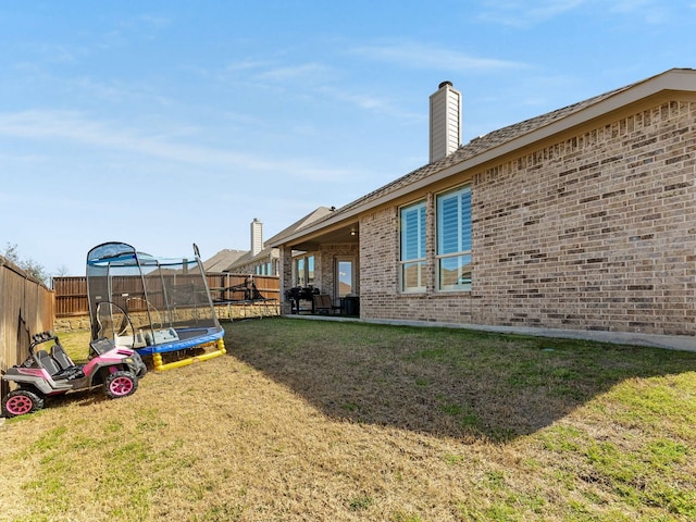 view of yard with a trampoline and a fenced backyard