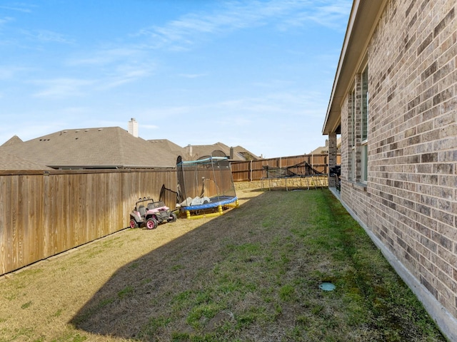 view of yard featuring a trampoline and a fenced backyard