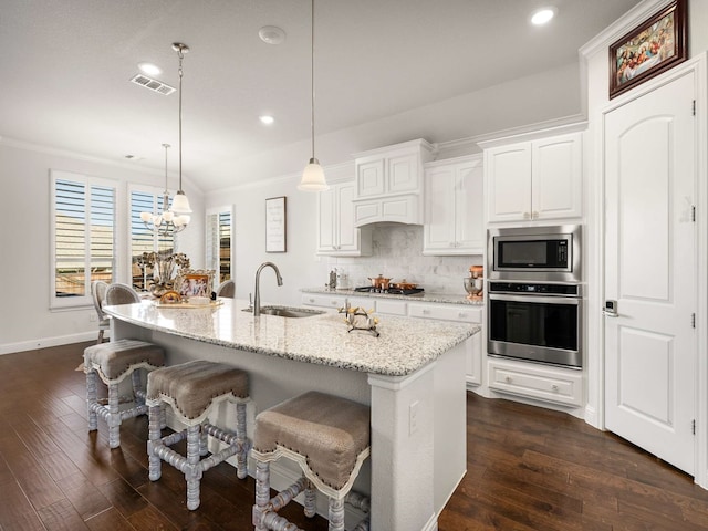 kitchen with stainless steel appliances, ornamental molding, dark wood-style flooring, and a sink